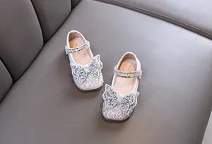 Primer plano de zapatos de princesa blancos para niña con mariposa de diamantes de imitación