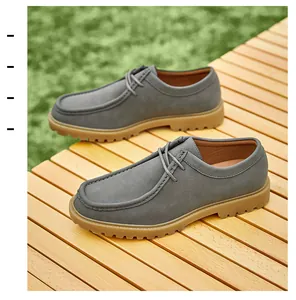 Close-up of grey leather Derby shoes with tan soles on a wooden outdoor surface.