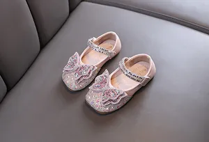Vista detallada de zapatos de princesa rosas para niña con lazo de diamantes de imitación.