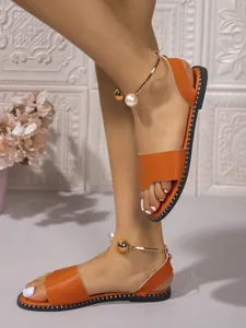 Sandales plates orange élégantes avec détail de bride de cheville en perles au pied