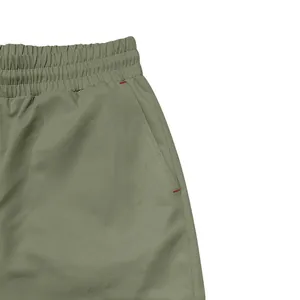 Close-up of men's cargo trousers showing elastic waist and side pocket with red bartacks