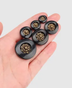 Detail view of assorted vintage black buttons with gold floral centers held in hand