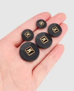 Detailed view of black nylon buttons with gold square metal centers in various sizes