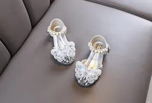 Detailed view of silver girl's princess shoes featuring a large sparkling rhinestone butterfly