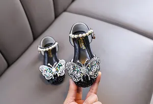 Close-up detail of girl's black princess shoes with rhinestone butterfly and pearl strap.
