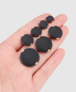 Detailed view of high-end black nylon buttons in various sizes held in hand