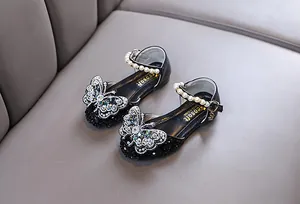 Detailed close-up of girls' black princess shoes with rhinestone butterfly and pearl strap