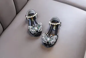 Detailed view of girls black princess shoes with rhinestone butterfly and pearl strap