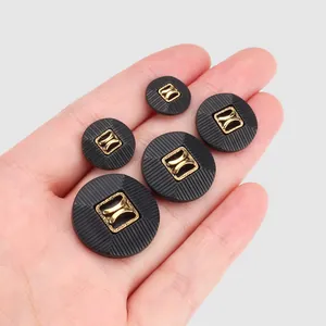 High-end black nylon garment buttons with gold center decoration shown in various sizes on hand