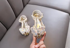 Girls' sparkly princess shoe detail featuring a rhinestone butterfly and pearl ankle strap.