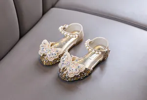 Close-up of girls' gold princess shoes with butterfly rhinestones and pearl straps