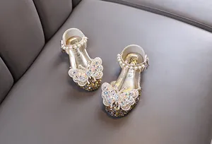 Close-up of girl's champagne gold princess shoes with rhinestones and pearl strap