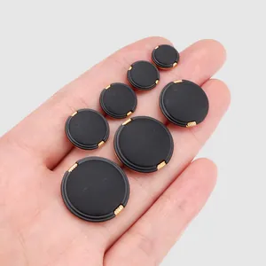 Collection of premium black nylon buttons with gold edges shown in hand for scale