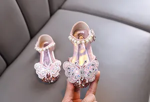 Detail of pink princess shoes for girls with rhinestone butterfly and pearl strap