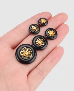 Detailed macro shot of black nylon buttons with gold floral center in various sizes.