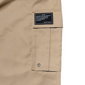 Close-up of side cargo pocket on khaki cotton pants with decorative black patch.