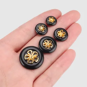Elegant black nylon buttons featuring decorative gold floral centers for luxury apparel.