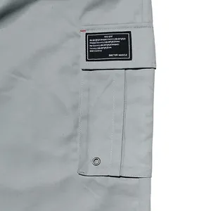 Close-up detail of cargo pocket with text patch on light grey men's casual work pants