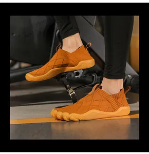 Detail showing orange flyknit barefoot shoes on exercise bike pedals in a gym setting
