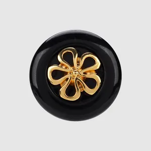 Elegant premium black circular button with a decorative golden flower-shaped metal inlay.