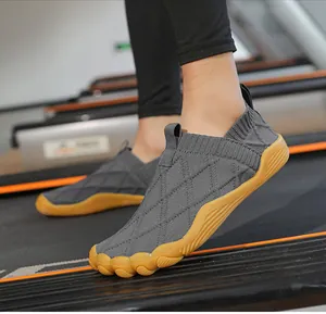 Side view of grey flyknit barefoot shoes with wide toe box and gum sole on a treadmill.