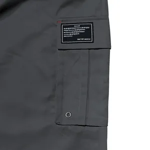 Close-up detail of large side cargo pocket on grey men's cargo pants with label