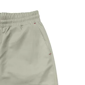 Close-up view of side pocket with red reinforced stitching on grey men's cargo pants