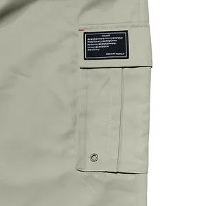 Close-up detail of pocket with black tag on men's casual cargo pants in sage green