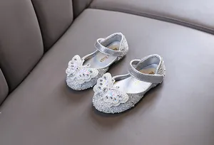 Elegant close-up of girls' silver glitter princess shoes with pearl butterfly decoration