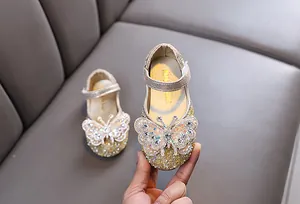 Close-up of the sparkling rhinestone butterfly on a golden glitter girl's princess shoe
