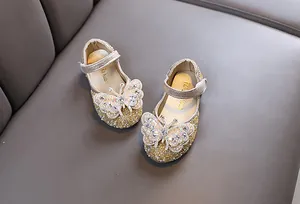 Detail of girls' gold rhinestone princess flats with butterfly ornament