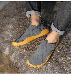 Detailed view of gray fly-knit barefoot hiking shoes with wide toe box on a rock
