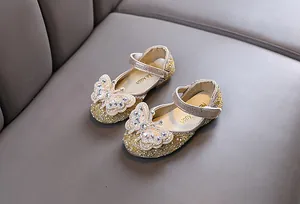 Close-up detail of glittering gold princess shoes for girls with pearl butterflies
