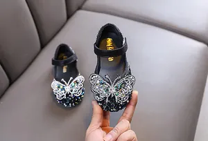 Close-up of girl's black princess shoes featuring a large sparkling butterfly rhinestone.