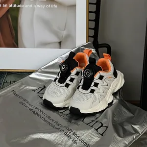 Primer plano de zapatillas chunky para niños en blanco y naranja con sistema de cierre giratorio