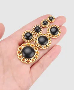 Close-up of elegant black and gold vintage decorative buttons in various sizes on a hand