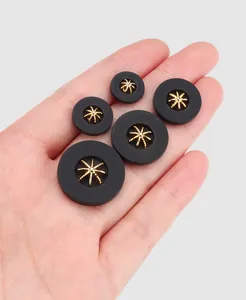 Close-up of black nylon buttons with golden star metal center in various sizes
