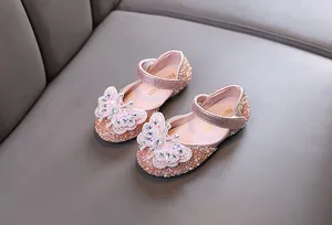Close-up of pink glittery girls princess shoes with sparkling rhinestone butterfly.