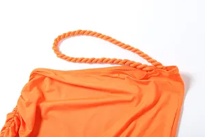 Detailansicht eines leuchtend orangen Oberteils mit einem dekorativen gedrehten Träger.