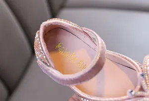 Close-up of pink girls princess shoes featuring sparkling rhinestones and gold branding