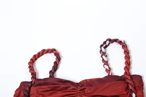 Detailansicht eines roten Camisole-Tops mit geflochtenen Trägern und plissierten Details.