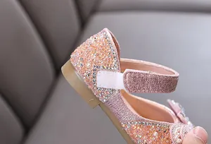 Close-up of girl's princess shoe featuring sparkling rhinestones, pearls, and velcro strap.