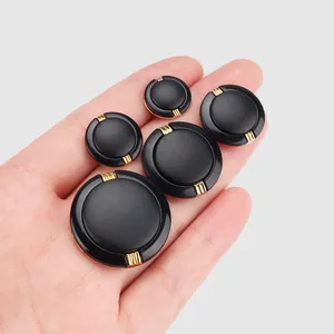 Premium set of black nylon buttons with gold accents held in hand for size reference.
