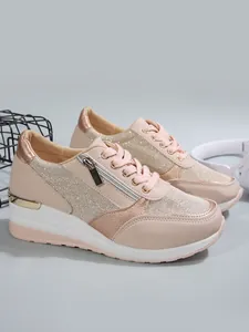 Close-up view of pink platform sneakers featuring rose gold glitter and side zipper details.
