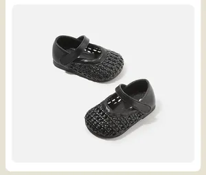 Macro view of black woven baby girl walking shoes with cut-out design and strap.