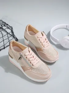 Close-up detail of stylish pink wedge sneakers featuring side zipper and glitter mesh panels