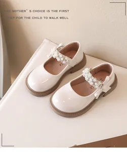 Detalle de zapatos Mary Jane blanco roto para niña con elegantes correas de perlas y pedrería.