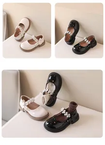 Vista detallada de zapatos Mary Jane para niñas en blanco y negro con correas de perlas y lazos.
