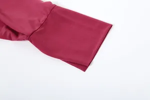 Dettaglio ravvicinato del polsino della manica di un abito a camicia bordeaux con trama