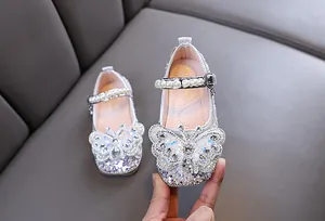 Détail de chaussures princesse argentées pour filles avec strass et papillon perlé.